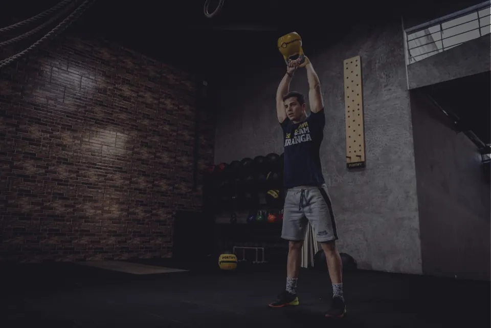 Aluno erguendo o kettlebell acima da cabeça